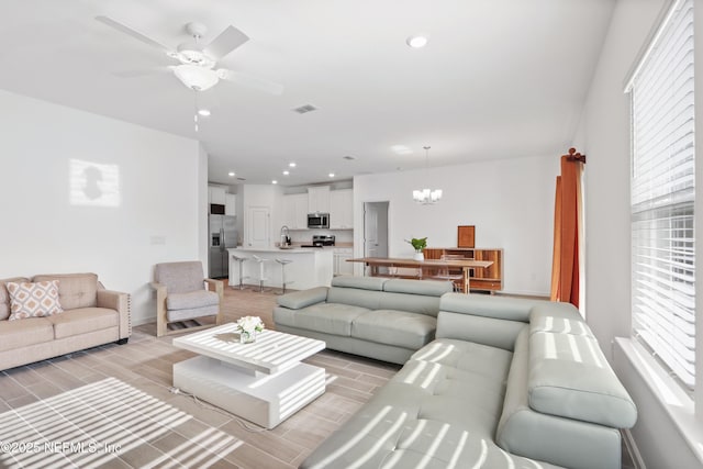 living room with sink and ceiling fan with notable chandelier