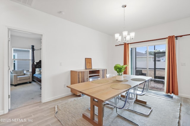 dining area with a chandelier, wood finish floors, visible vents, and baseboards