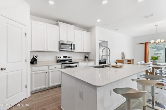 kitchen featuring white cabinetry, an island with sink, pendant lighting, and appliances with stainless steel finishes