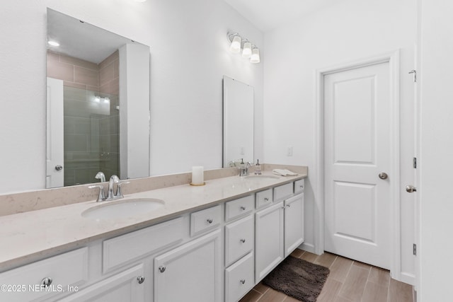 full bath featuring wood tiled floor, a sink, a shower stall, and double vanity