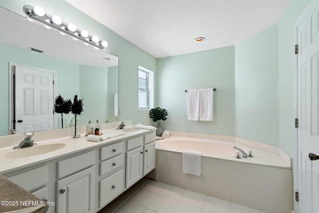 bathroom with tile patterned flooring, vanity, a textured ceiling, and a tub to relax in