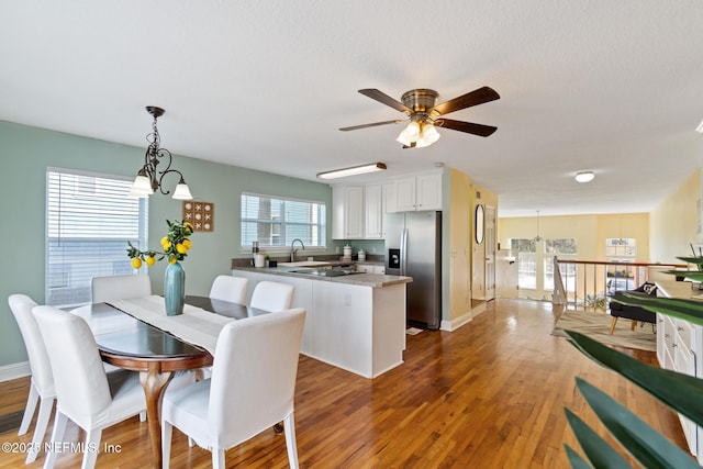 dining area featuring ceiling fan with notable chandelier, dark hardwood / wood-style floors, and sink