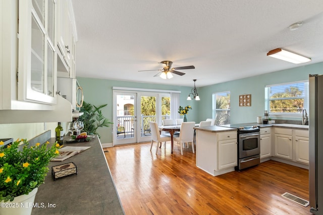 kitchen featuring decorative light fixtures, white cabinets, dark hardwood / wood-style flooring, kitchen peninsula, and stainless steel appliances