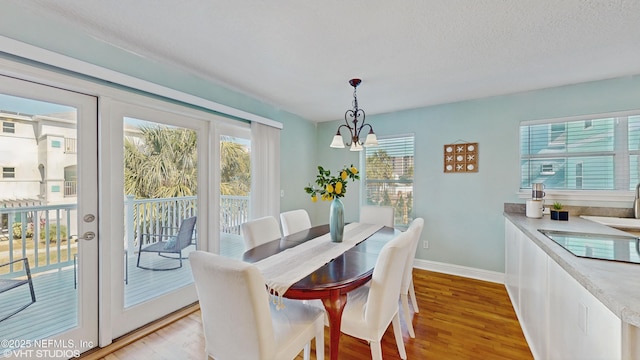 dining room featuring a chandelier, a textured ceiling, light hardwood / wood-style flooring, and a wealth of natural light