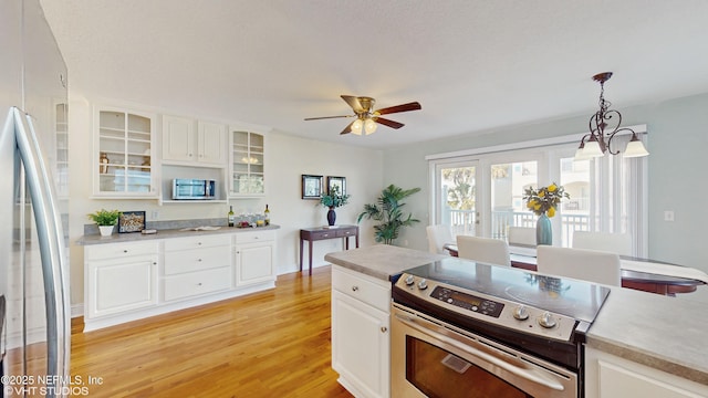 kitchen featuring white cabinetry, decorative light fixtures, ceiling fan, stainless steel appliances, and light hardwood / wood-style floors