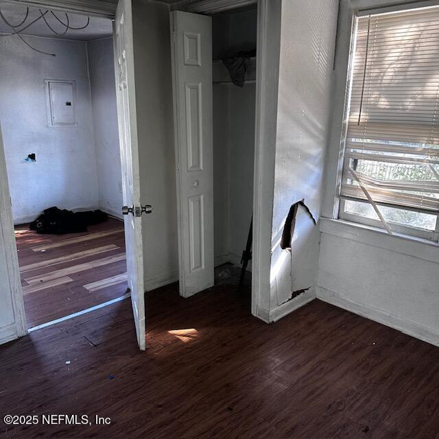 unfurnished bedroom with dark hardwood / wood-style floors, electric panel, and a closet