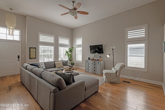 living room featuring ceiling fan with notable chandelier and light wood-type flooring