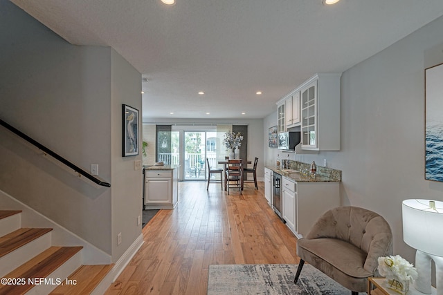 kitchen featuring white cabinets, light wood-type flooring, and light stone counters