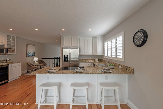 kitchen with kitchen peninsula, white cabinetry, sink, and stainless steel appliances