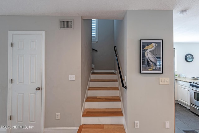 stairway featuring hardwood / wood-style flooring and a textured ceiling