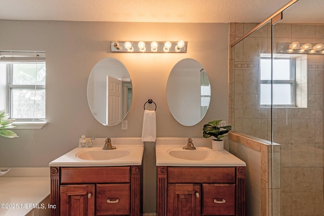 bathroom with vanity, a shower with shower door, and a textured ceiling