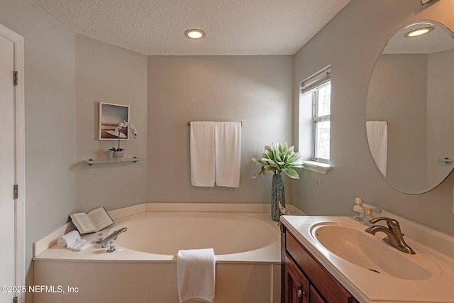 bathroom featuring vanity, a textured ceiling, and a tub