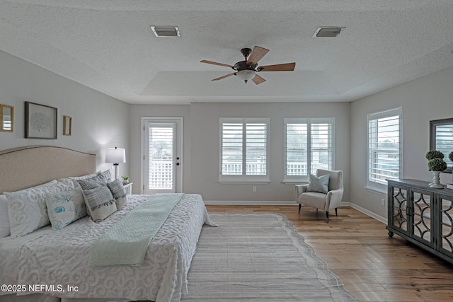 bedroom with access to exterior, multiple windows, a tray ceiling, and ceiling fan