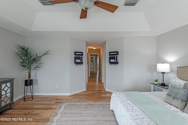 bedroom featuring a tray ceiling, ceiling fan, and light hardwood / wood-style floors