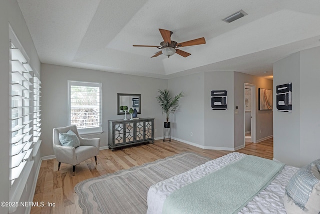 bedroom featuring a raised ceiling, ceiling fan, a textured ceiling, and hardwood / wood-style flooring