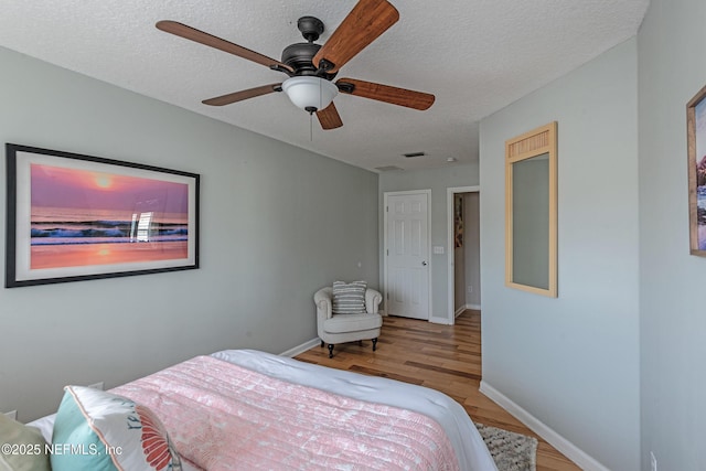 bedroom with ceiling fan, light hardwood / wood-style floors, and a textured ceiling