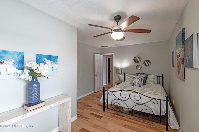 bedroom featuring ceiling fan, a textured ceiling, and light hardwood / wood-style flooring