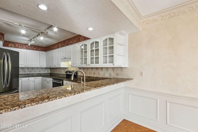 kitchen featuring a textured ceiling, dark stone countertops, kitchen peninsula, stainless steel appliances, and white cabinets