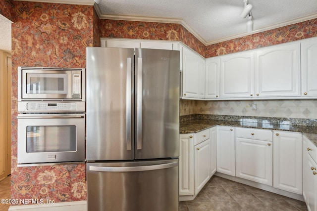 kitchen featuring white cabinetry, dark stone countertops, light tile patterned floors, stainless steel appliances, and a textured ceiling