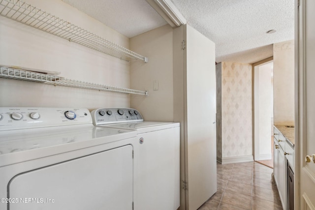 washroom with washer and clothes dryer, a textured ceiling, and light tile patterned flooring