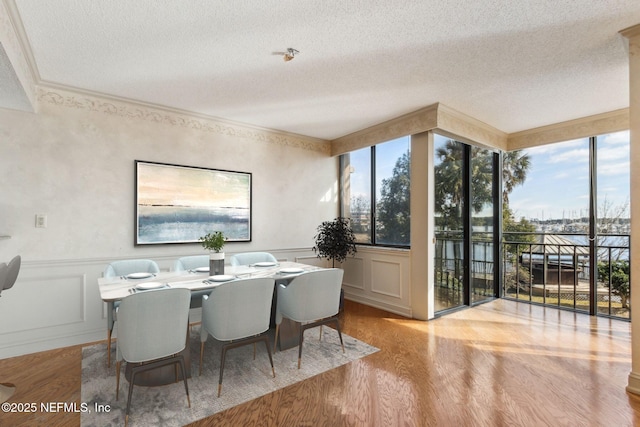 dining room featuring crown molding, light hardwood / wood-style flooring, and a textured ceiling