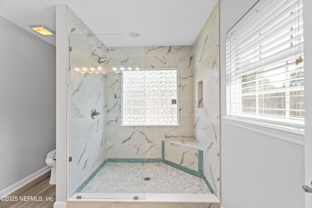 bathroom featuring toilet, tiled shower, a wealth of natural light, and hardwood / wood-style floors