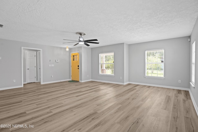 unfurnished room featuring light wood-type flooring, ceiling fan, a textured ceiling, and plenty of natural light