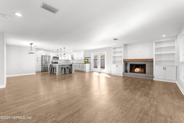 unfurnished living room featuring a textured ceiling and light hardwood / wood-style flooring