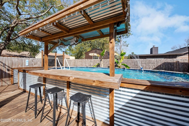 view of pool with an outdoor bar and a wooden deck