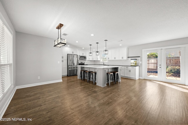 kitchen featuring a center island, a breakfast bar area, decorative light fixtures, white cabinetry, and stainless steel appliances