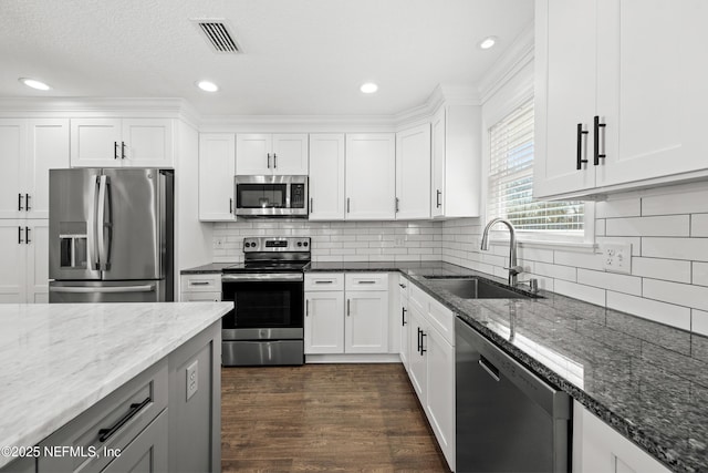 kitchen featuring sink, light stone counters, dark hardwood / wood-style floors, white cabinets, and appliances with stainless steel finishes