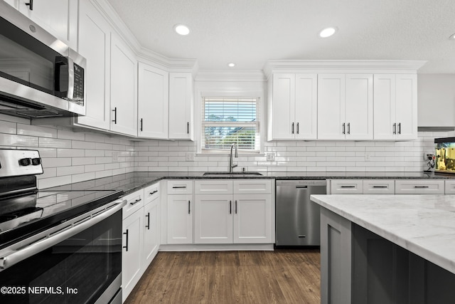 kitchen featuring backsplash, white cabinets, sink, dark stone countertops, and appliances with stainless steel finishes