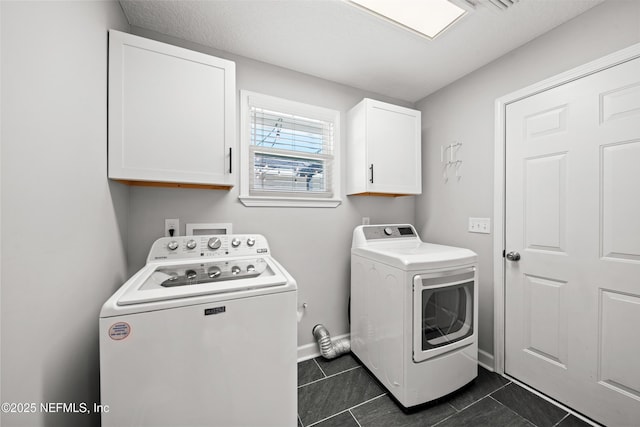 laundry room featuring cabinets, dark tile patterned floors, and washing machine and clothes dryer