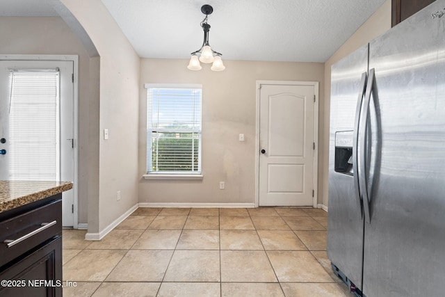 kitchen featuring hanging light fixtures, stainless steel fridge with ice dispenser, a notable chandelier, stone countertops, and light tile patterned floors