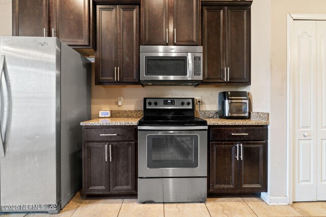 kitchen with appliances with stainless steel finishes, dark brown cabinetry, and light tile patterned floors