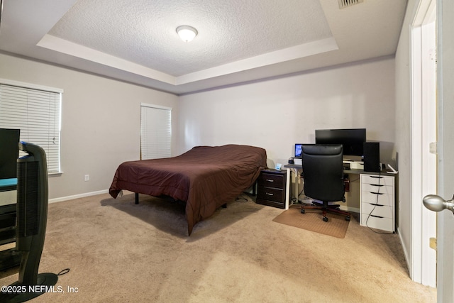 carpeted bedroom featuring a textured ceiling and a raised ceiling