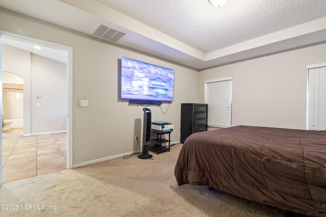 carpeted bedroom with ensuite bathroom and a textured ceiling