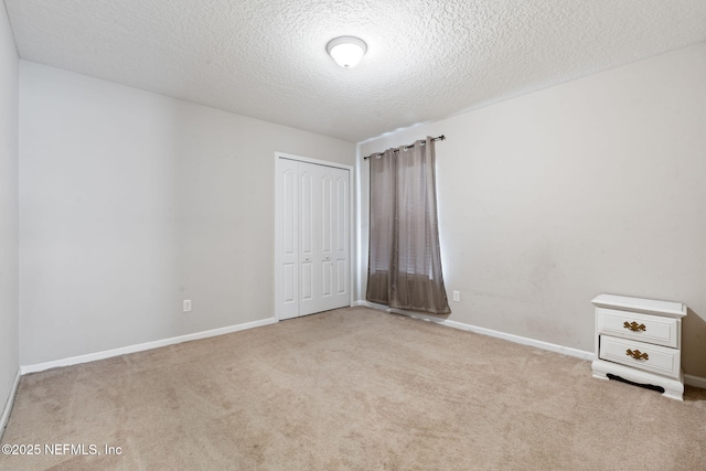 unfurnished bedroom featuring a closet, light colored carpet, and a textured ceiling