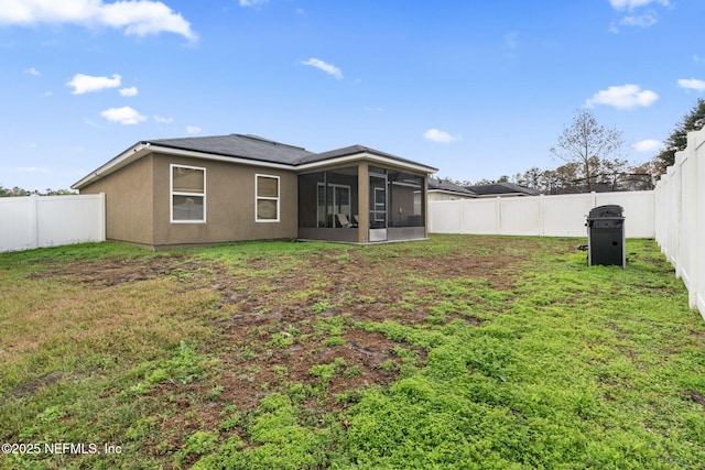 rear view of property featuring a sunroom and a lawn