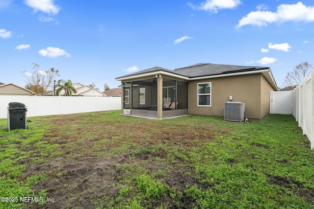 rear view of property with a sunroom, central air condition unit, and a yard