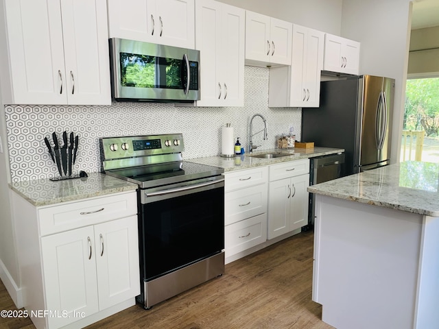 kitchen with backsplash, stainless steel appliances, sink, white cabinets, and hardwood / wood-style floors