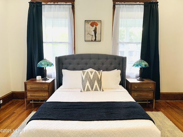 bedroom with dark hardwood / wood-style floors and multiple windows