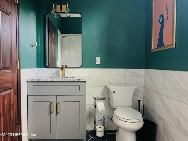 bathroom featuring vanity, toilet, and tile walls