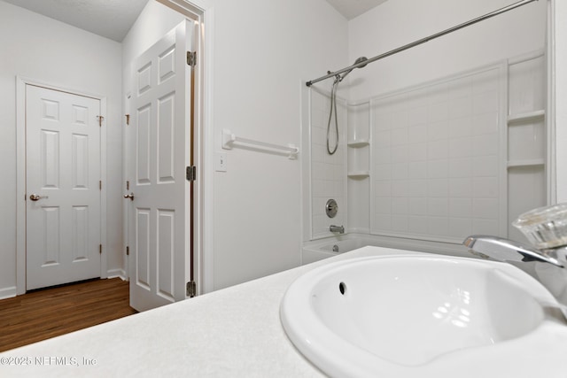 bathroom with wood-type flooring, sink, and bathtub / shower combination