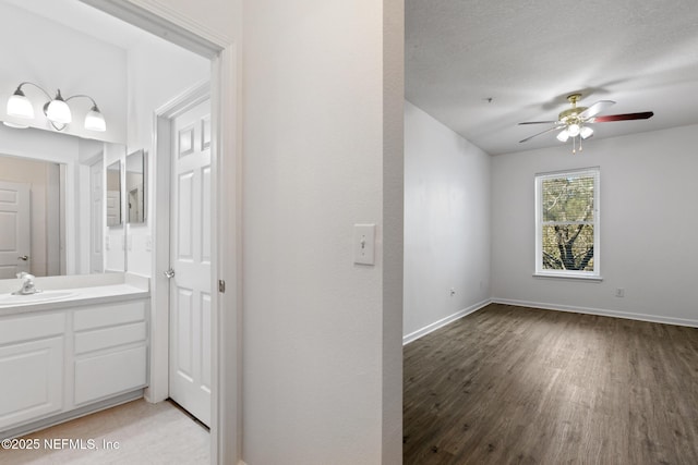 bathroom with ceiling fan, hardwood / wood-style floors, vanity, and a textured ceiling