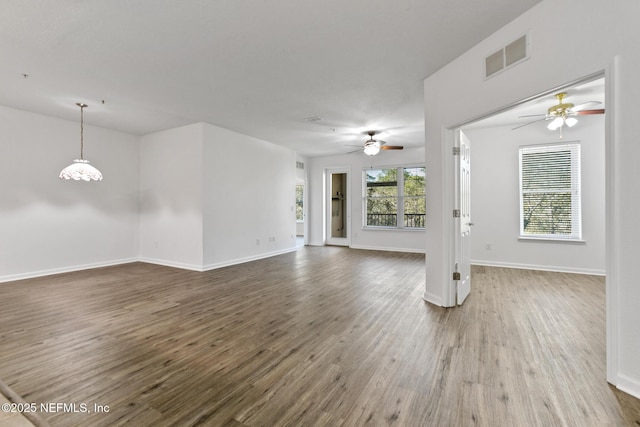 unfurnished living room featuring wood-type flooring and ceiling fan with notable chandelier