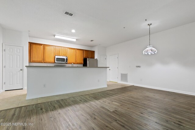 kitchen featuring a center island, stainless steel appliances, hanging light fixtures, and hardwood / wood-style flooring