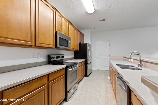 kitchen with a textured ceiling, sink, and appliances with stainless steel finishes