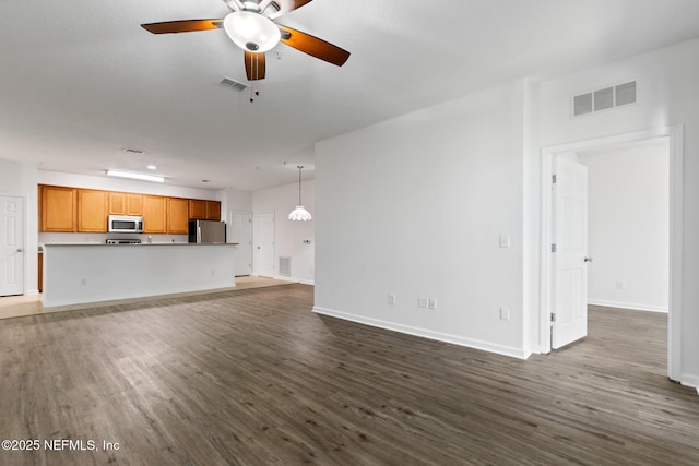 unfurnished living room featuring ceiling fan and dark wood-type flooring