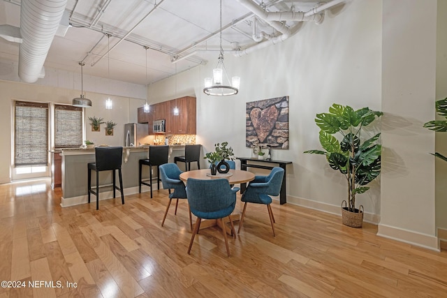 dining room with a chandelier, light hardwood / wood-style floors, and a high ceiling